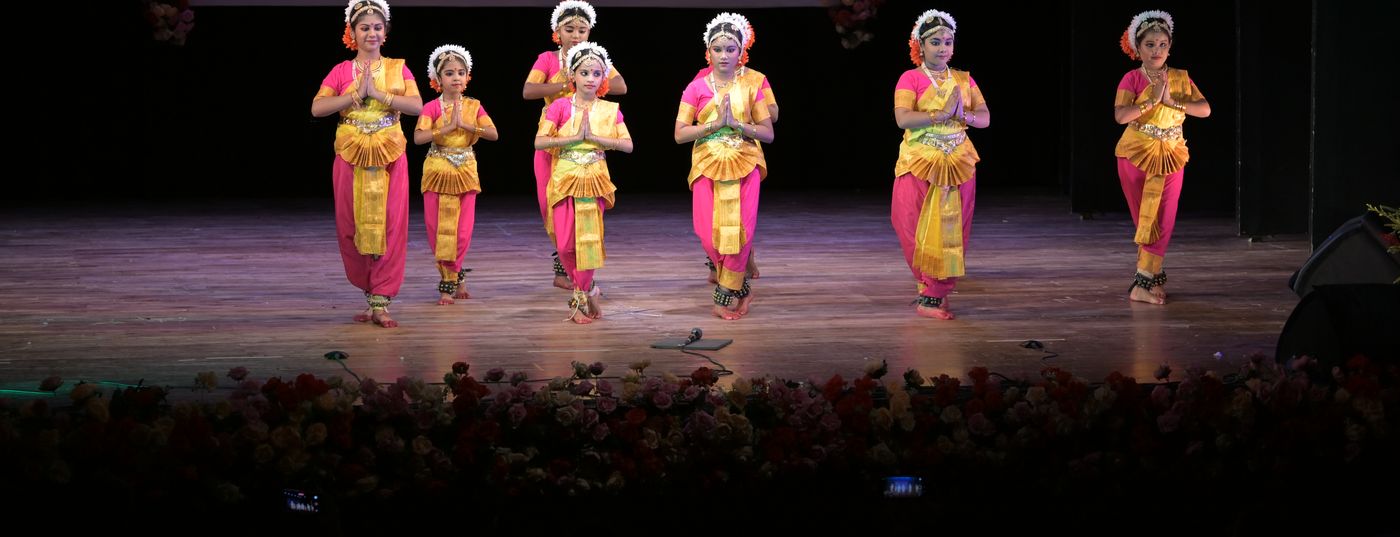 A row of young Bharatanatyam students performing together on stage