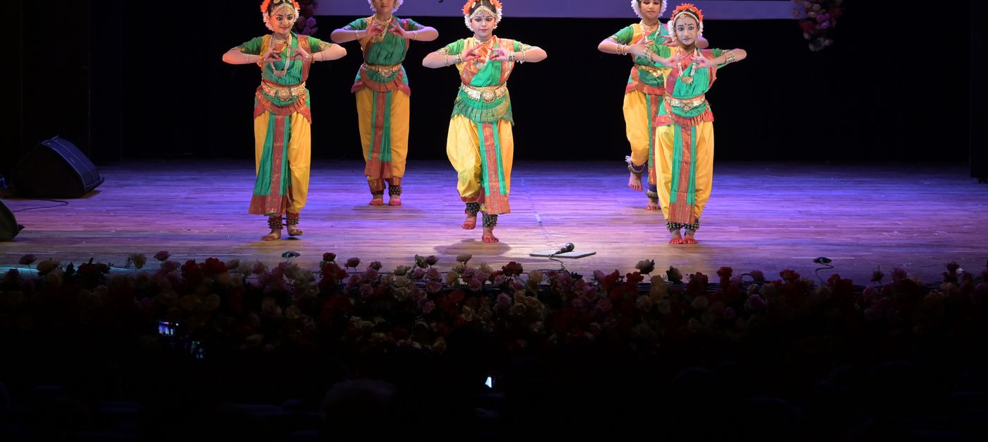 Bharatanatyam students in green and gold costumes performing together on stage