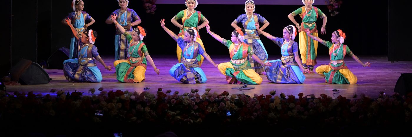 A larger group of Bharatanatyam students performing a seated formation