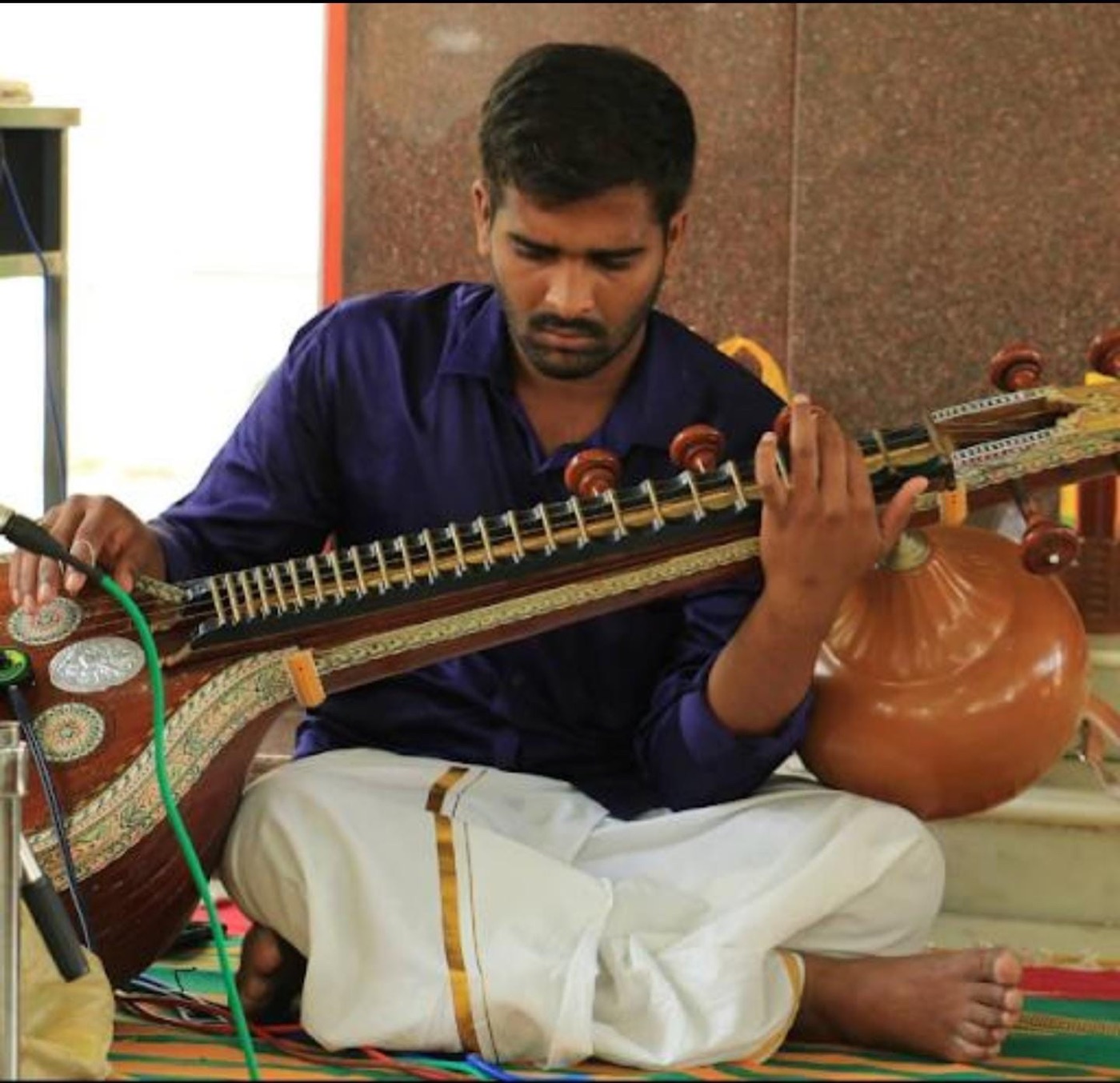 Carnatic musician playing a veena in quiet concentration