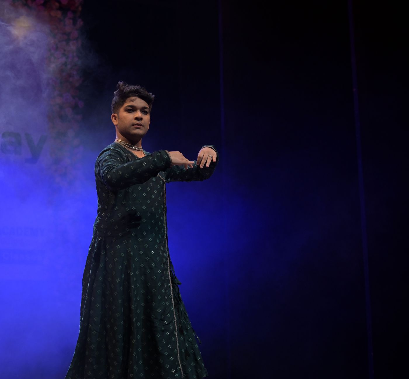 Kathak dancer in a still, poised stance under blue stage light