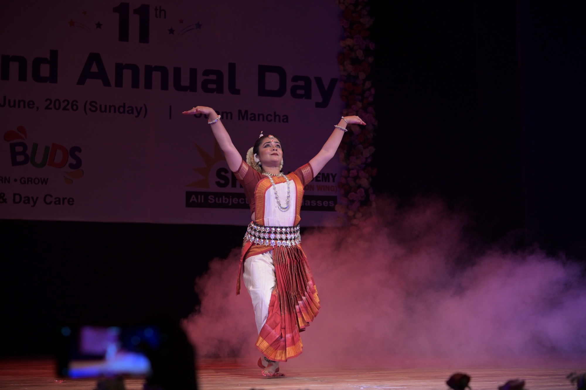 Odissi dancer with both arms raised in a joyful, triumphant pose