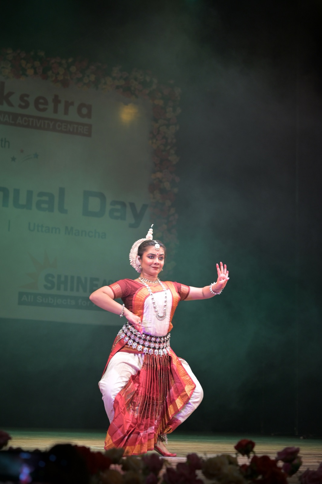 Odissi dancer balanced on one leg with hands raised in a sculptural gesture